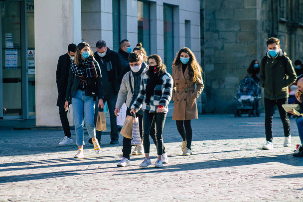 ランスフランス2021年1月9日フランスに影響を与えるパンデミックの間、ランスの通りを歩くコロナウイルスから身を守るために顔マスクを持つ未確認の歩行者の眺め - 写真・画像