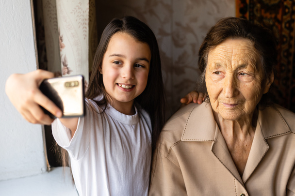 曾祖母と孫娘でスマートフォンを持っています - 写真・画像