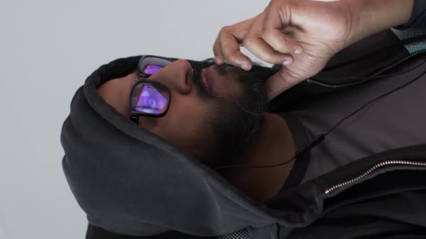 Mannelijke dragen Hoodie Draaien op stoel met computerschermen weerspiegeld in bril. Verticale video, afgesloten - Video