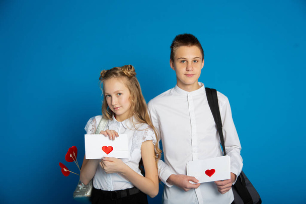 A couple of schoolchildren are teenagers on Valentine's Day on a blue background - Valokuva, kuva
