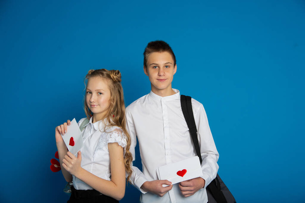 A couple of schoolchildren are teenagers on Valentine's Day on a blue background - Fotó, kép
