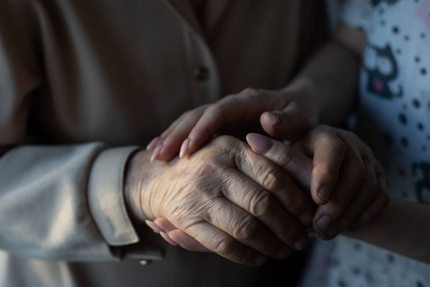 zeer oudere overgrootmoeder en kleindochter houden elkaars hand vast - Foto, afbeelding