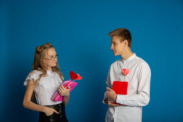 A couple of schoolchildren are teenagers on Valentine's Day on a blue background - Foto, Imagen