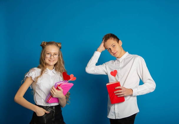 A couple of schoolchildren are teenagers on Valentine's Day on a blue background - Zdjęcie, obraz