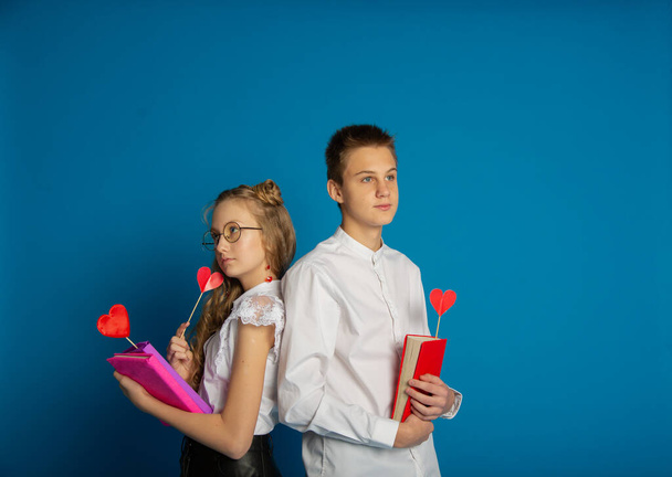 A couple of schoolchildren are teenagers on Valentine's Day on a blue background - Foto, imagen