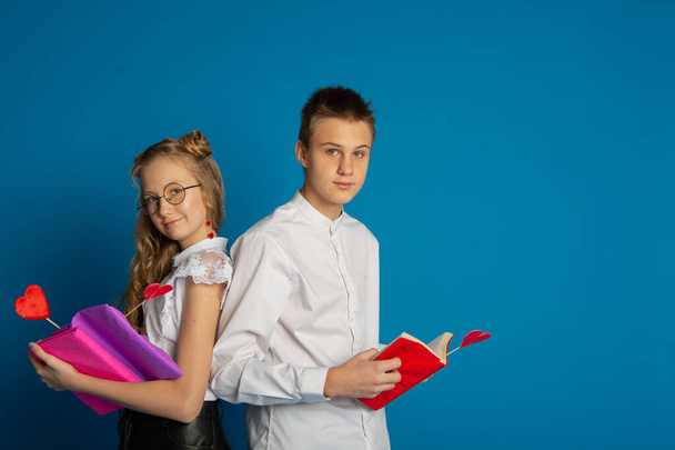 Um par de crianças em idade escolar são adolescentes no Dia dos Namorados em um fundo azul - Foto, Imagem