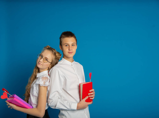 A couple of schoolchildren are teenagers on Valentine's Day on a blue background - Φωτογραφία, εικόνα