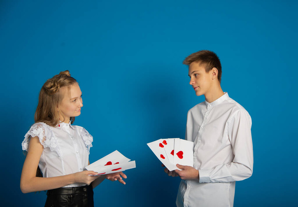 A couple of schoolchildren are teenagers on Valentine's Day on a blue background - Photo, image