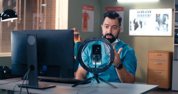 Бородатий чоловік лікар робить відеодзвінок колегам
 - Фото, зображення