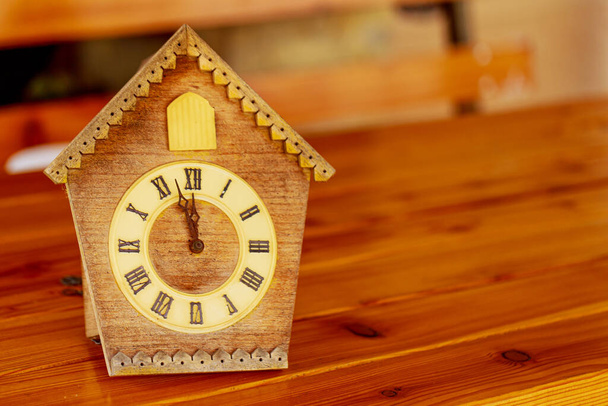 Годинник ретро зозулі з римськими цифрами на дерев'яному столі. На годиннику 12 годин без 5 хвилин.. - Фото, зображення