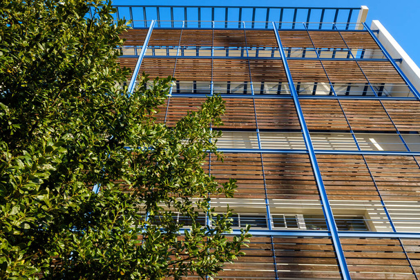Edificio moderno con tablas de madera en la fachada para protegerse del sol y ser de construcción sostenible. - Foto, Imagen
