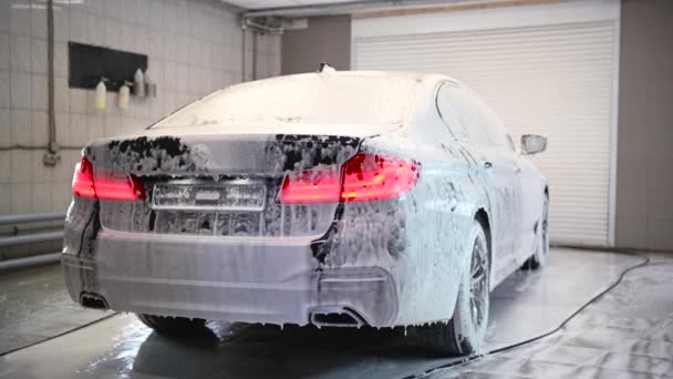 The car is covered with white flowing foam at a car wash. Timelapse. - Footage, Video