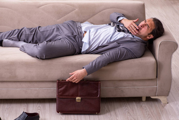 Уставший молодой бизнесмен возвращается домой после рабочего дня - Фото, изображение