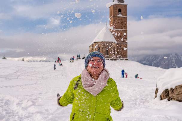 Frau, die sich im Schnee amüsiert, lächelt, als ihr Schnee entgegen geworfen wird; Freizeitaktives Winterkonzept; - Foto, Bild