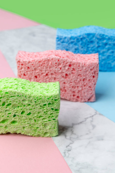 Creative layout with sponges for dishwashing on multicolor background - Фото, зображення