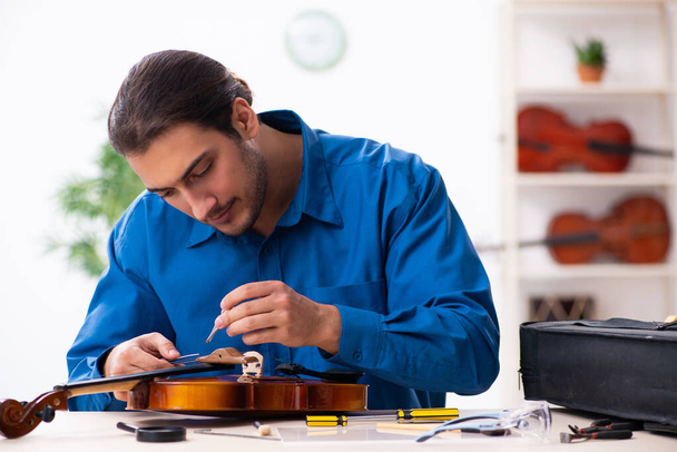 Молодий чоловік ремонтує скрипку
 - Фото, зображення