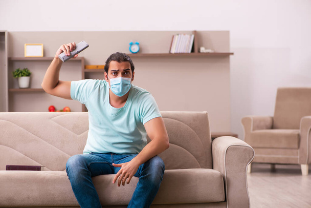 Młody mężczyzna ogląda telewizję w domu podczas pandemii - Zdjęcie, obraz