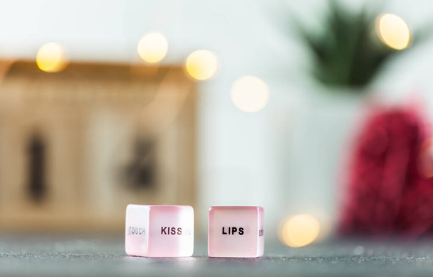 Macro shot des dés roses avec des lèvres baiser texte sur eux. Fond flou avec des lumières bokeh. Bonne Saint-Valentin. Jeu d'amour. Jeux d'argent - Photo, image