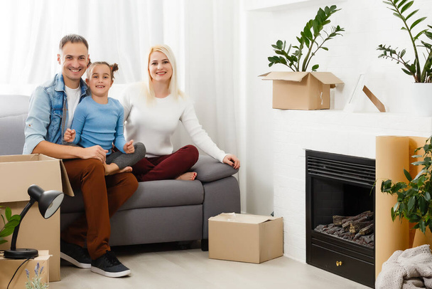 Happy family sitting on wooden floor. Father, mother and child having fun together. Moving house day, new home and design interior concept - Photo, Image