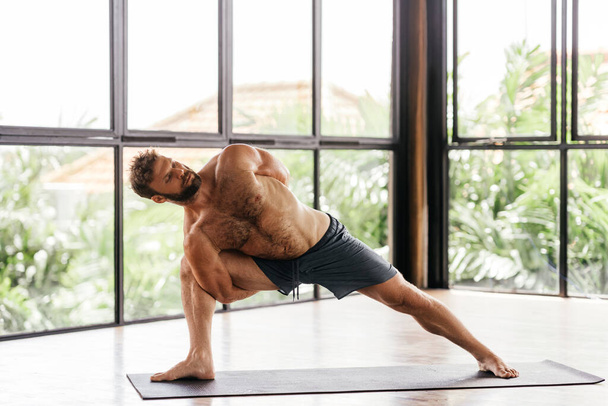 Yoga άνδρες προπόνηση στο στούντιο μπροστά από ένα παράθυρο - Φωτογραφία, εικόνα