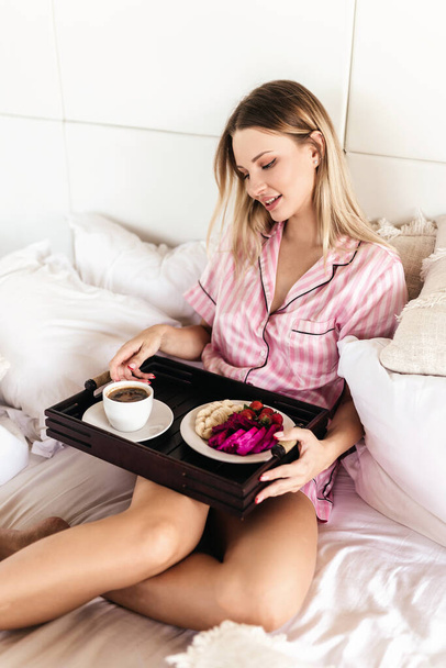 Young woman working at home in the bedroom during morning breakfast - Foto, afbeelding
