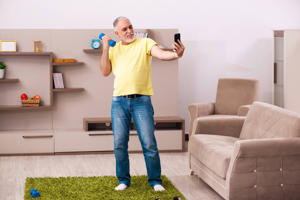 Aged man doing sport exercises at home - Foto, imagen