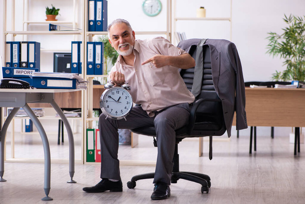 Старый работник-мужчина делает физические упражнения в ко-управлении временем - Фото, изображение