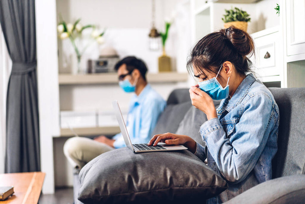 Genç Asyalı çift dizüstü bilgisayar kullanıyor ve Coronavirus için karantinada görüntülü görüşme yapıyor. Ev konseptinden sosyal mesafeli koruyucu maske takıyorlar. - Fotoğraf, Görsel