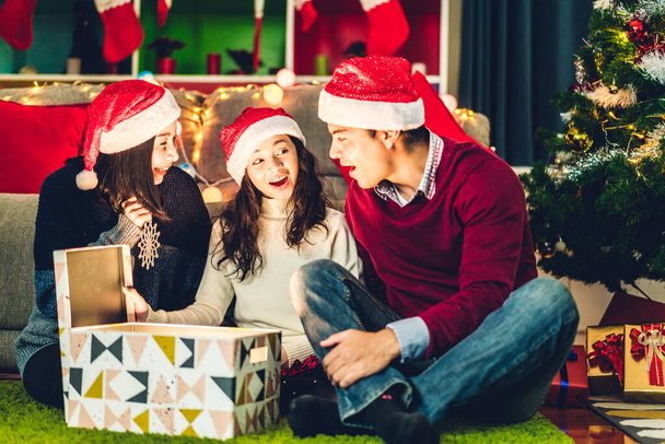 サンタの帽子の娘と幸せな家族の父親と母親の肖像は、魔法のクリスマスギフトボックスを開き、自宅でクリスマスの時間に一緒に過ごすことを楽しんでいます - 写真・画像