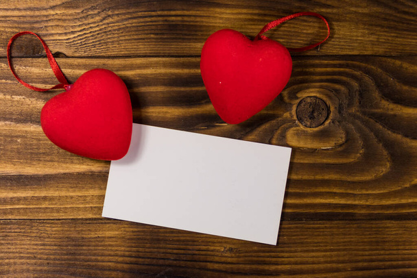 Valentijnsdag blanco wenskaart en twee rode harten op houten achtergrond. Bovenaanzicht, kopieer ruimte - Foto, afbeelding