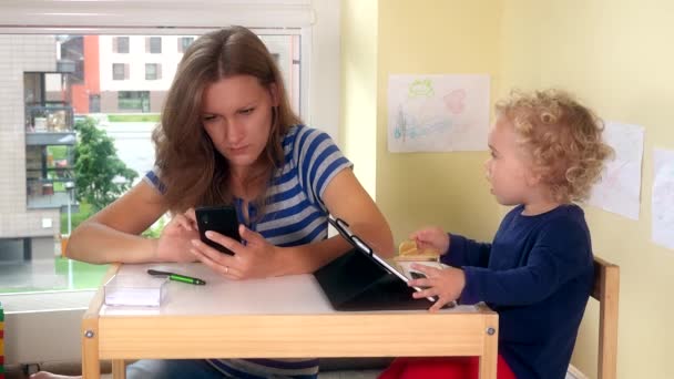 anya és aranyos baba használja okos média telefon és tabletta. 4K - Felvétel, videó