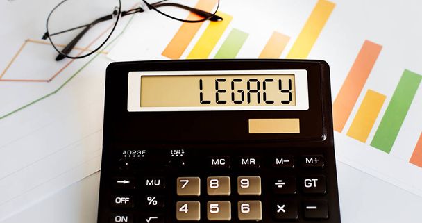 calculator with the word LEGACY on the display with chart and glasses. Business - Photo, Image