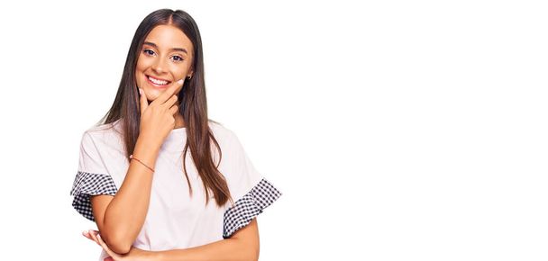 Young hispanic woman wearing casual clothes looking confident at the camera smiling with crossed arms and hand raised on chin. thinking positive.  - Foto, Bild