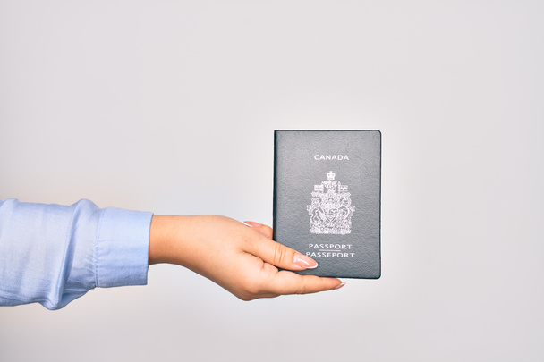 Рука кавказької молодої жінки, яка тримає в Канаді паспортний документ на ізольованому білому тлі. - Фото, зображення