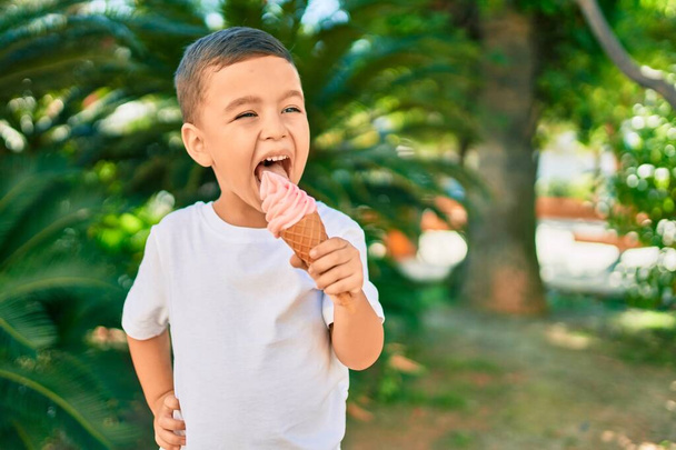 Adorable hispanic boy smiling happy eating ice cream at the park. - Foto, imagen