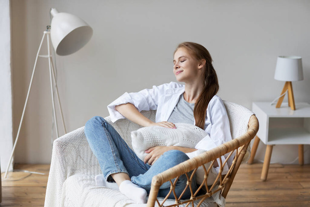 Relaxed smiling woman sitting on a chair at home. Domestic life. - Foto, afbeelding