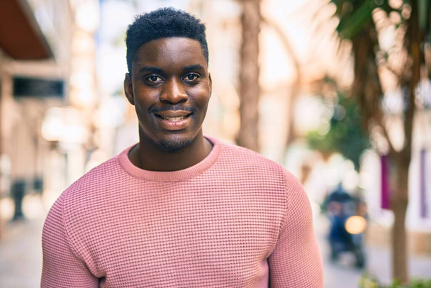 A fiatal afro-amerikai férfi boldogan mosolyog a városban.. - Fotó, kép
