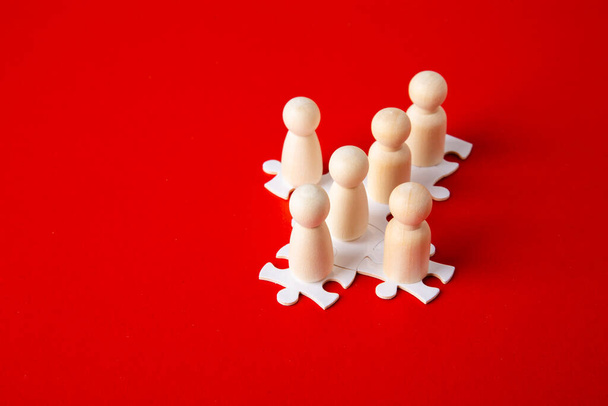 Figure in legno su puzzle su sfondo rosso come simbolo di team building. Gente del gruppo organizzativo in affari. Cooperazione e partenariato. - Foto, immagini