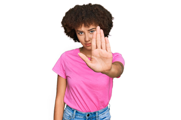 Jong Spaans meisje in casual kleding doet stoppen met zingen met de palm van de hand. waarschuwingsuitdrukking met negatief en ernstig gebaar op het gezicht.  - Foto, afbeelding