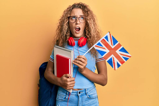 Gyönyörű kaukázusi tinédzser lány csere diák tartja UK zászló dühös és őrült sikoltozó frusztrált és dühös, kiabál a harag. düh és agresszív koncepció.  - Fotó, kép