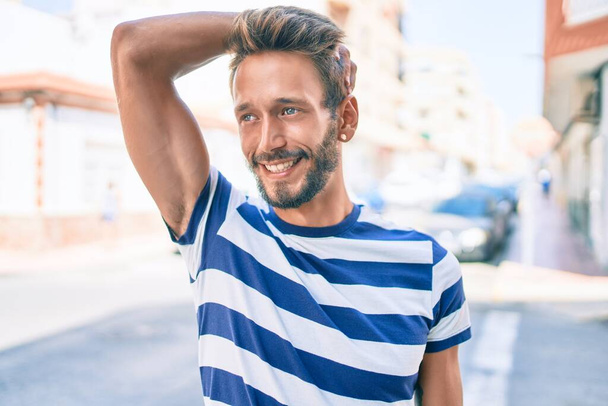 Schöner kaukasischer Mann mit Bart, der im Freien glücklich lächelt - Foto, Bild