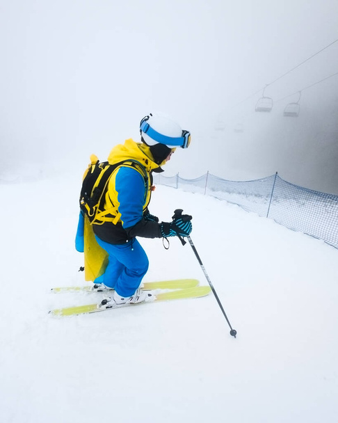 młoda kobieta narciarz ślizgające się po śniegu zboczu mgła zima pogoda kopia przestrzeń. - Zdjęcie, obraz