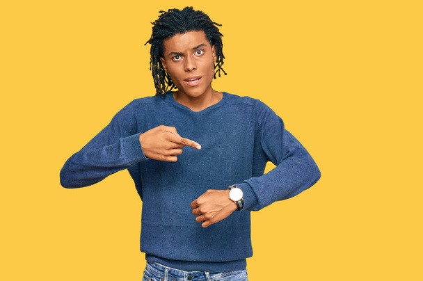 молодий афроамериканець у повсякденному зимовому светрі поспішає вказувати на час, нетерплячість, розстроєння і гнів через запізнення.  - Фото, зображення