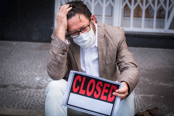 Portrait of desperate man wear medical mask for coronavirus economy crisis with closed business and for sale panel - Fotoğraf, Görsel
