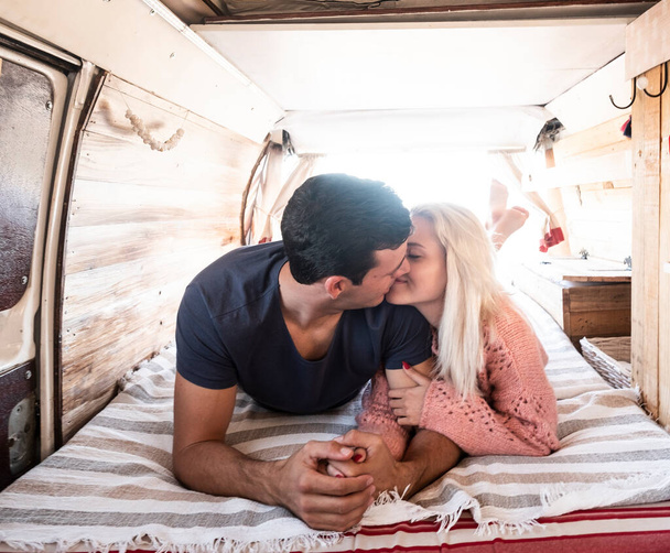 Love and travel with young couple kiss and love inside a trendy van vehicle during life or vacation leisure activity  - Valokuva, kuva
