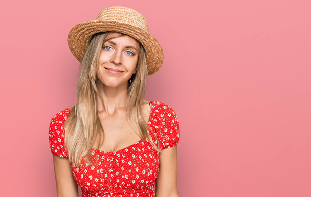 Beautiful caucasian woman wearing summer hat relaxed with serious expression on face. simple and natural looking at the camera.  - Foto, imagen