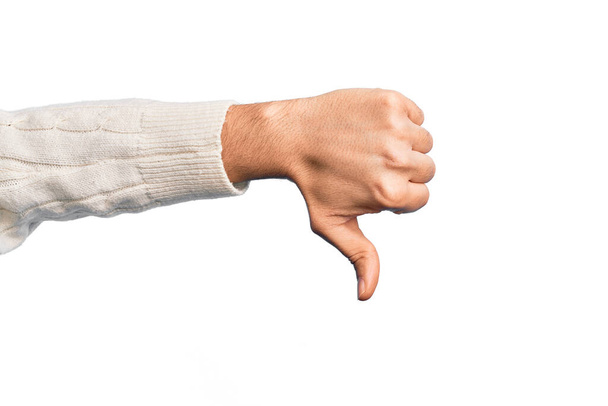Hand van blanke jongeman met vingers over geïsoleerde witte achtergrond die duimen naar beneden doet afwijzing gebaar, afkeuring afkeer en negatief teken - Foto, afbeelding