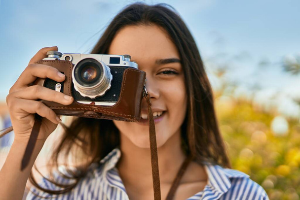 Młoda latynoska turystka uśmiecha się szczęśliwa korzystając z kamery w parku - Zdjęcie, obraz