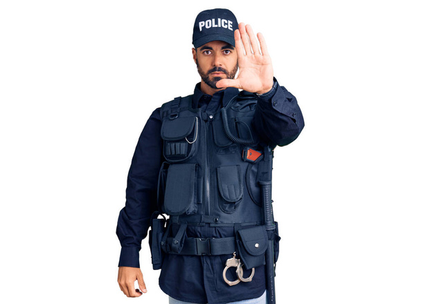 若いヒスパニック系の男は手の手のひらで歌うのを停止する警察の制服を着ている。顔に負の重大なジェスチャーで.  - 写真・画像