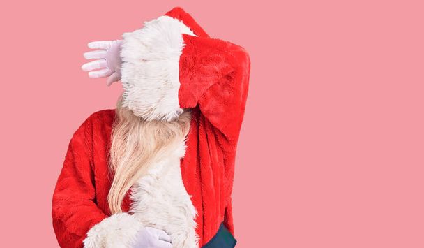 Starý starší muž s šedivými vlasy a dlouhými vousy v tradičním kostýmu Santa Clause, zakrývajícím oči paží, vypadal vážně a smutně. nevidomý, skrývající a odmítavý koncept  - Fotografie, Obrázek